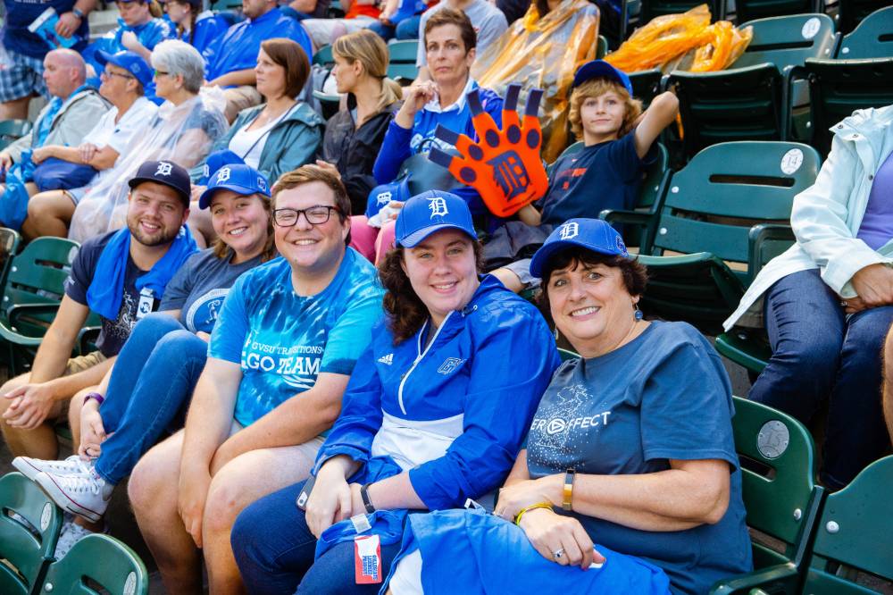 Five fans in gvsu night tigers hats are turned and facing the camera, all smiling